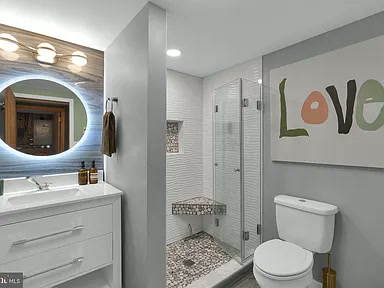 Renovated bathroom with pebble-tile walk-in shower, floating vanity and lit mirror