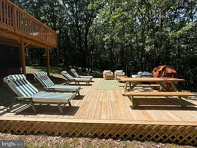 Elevated deck with outdoor sectional and dining table surrounded by forest