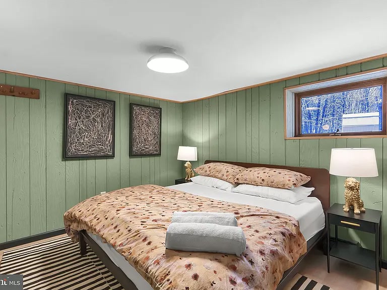Primary bedroom with king bed, walnut desk and wooded views